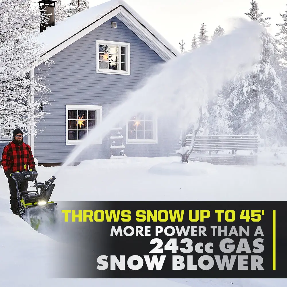 Ryobi snow blower throwing snow beside a stone wall