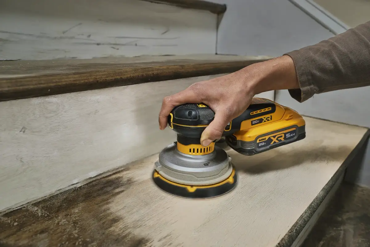 ਲੱਕੜ ਦੀ ਪੌੜੀ ਦੇ ਡੰਡੇ ਉੱਤੇ ਵਰਤੀ ਜਾ ਰਹੀ DEWALT 20V MAX XR ਸੈਂਡਰ