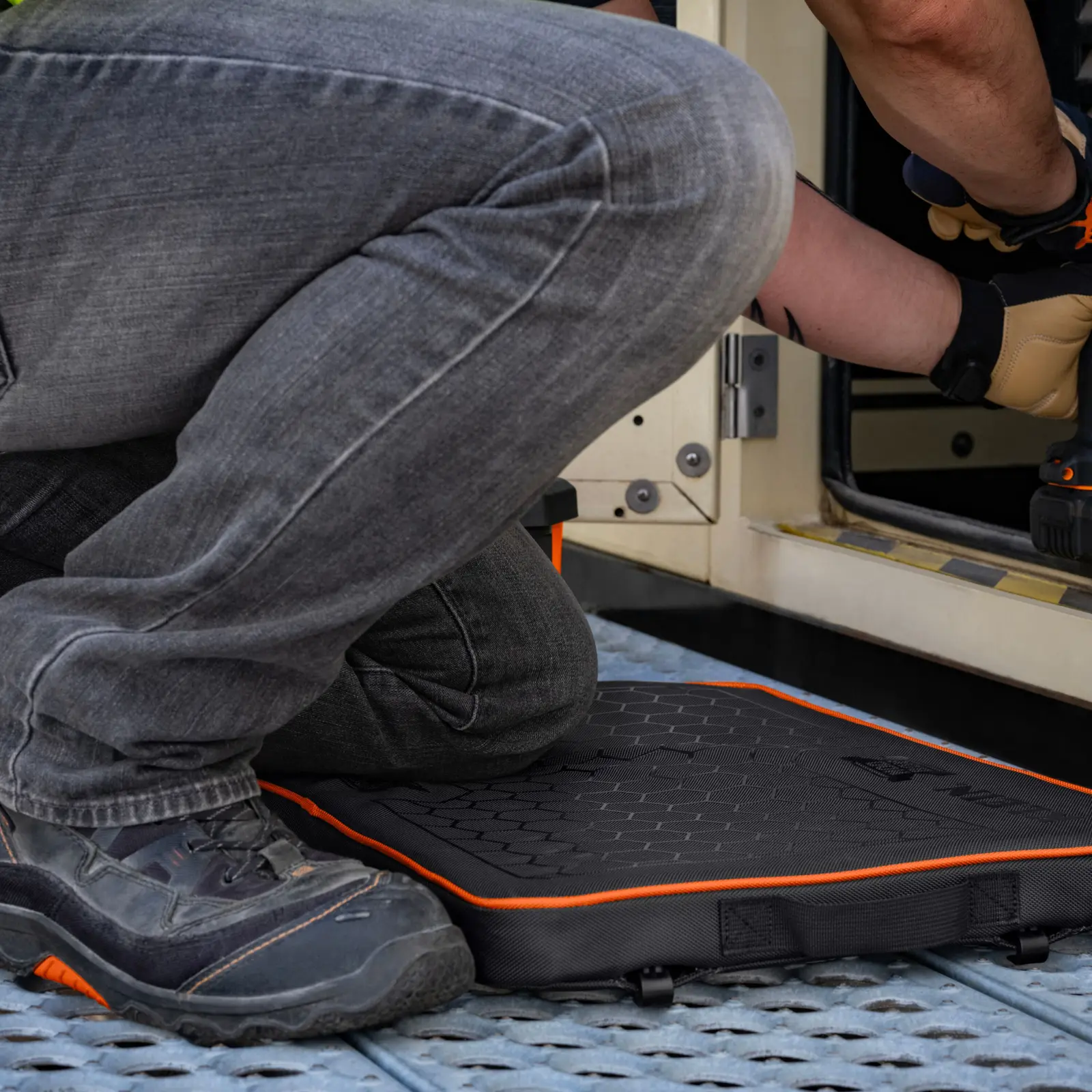 Worker kneeling on the Klein Tools MODbox kneeling pad beside a doorway