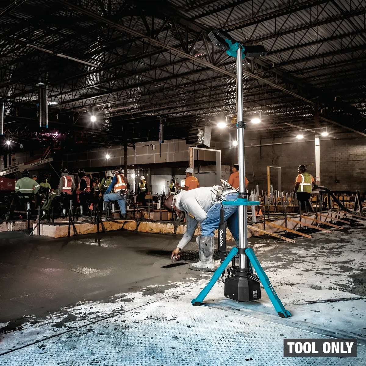 Lampe tour éclairant une équipe qui finit un plancher de béton