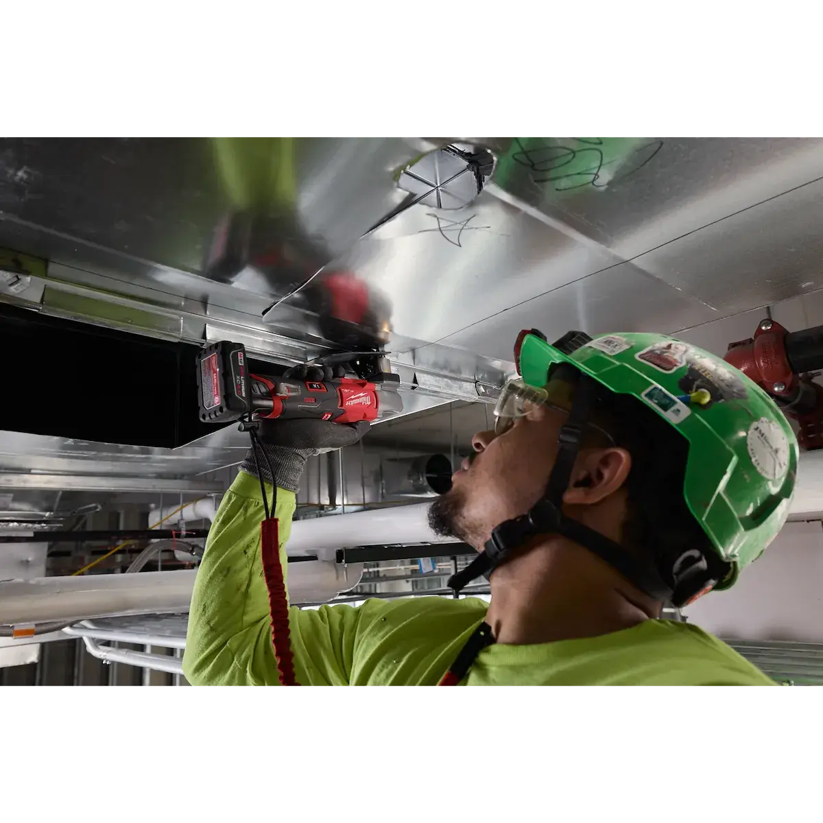 Installer using the scroll shear on overhead ductwork