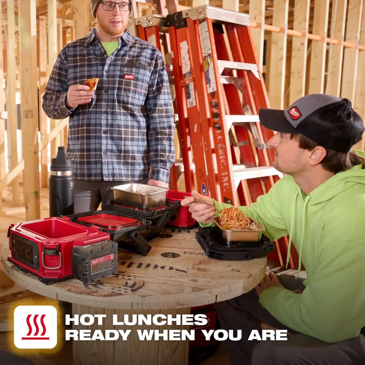 Two workers eating hot lunch from the Milwaukee warmer on a framing site